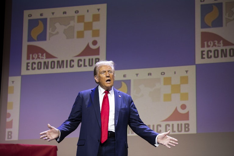 Donald Trump holds his arms out while speaking at the Detroit Economic Club