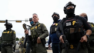 Border Patrol chief Greg Bovino walks with five masked officers.