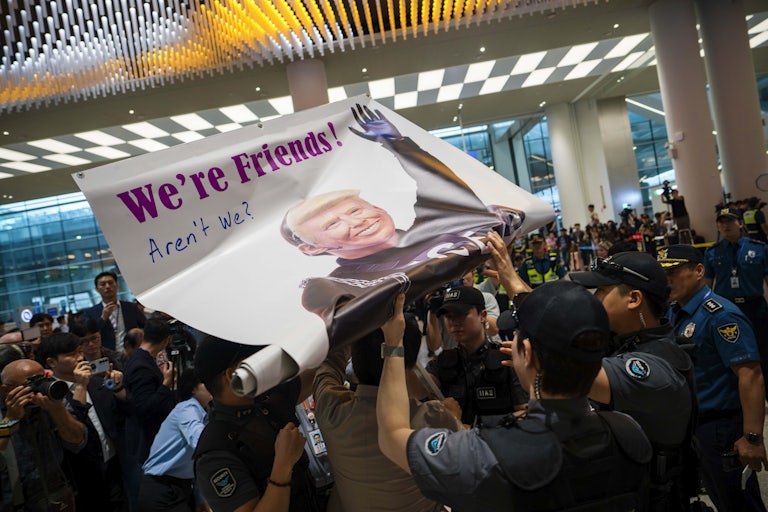 Protesters unfurl a banner depicting Donald Trump as an ICE agent reading "We're Friends... aren't we?"