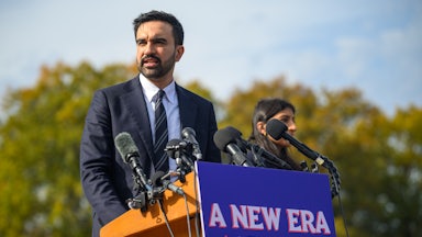 Zohran Mamdani speaks at a lectern with a sign that reads "A New Era for New York City."