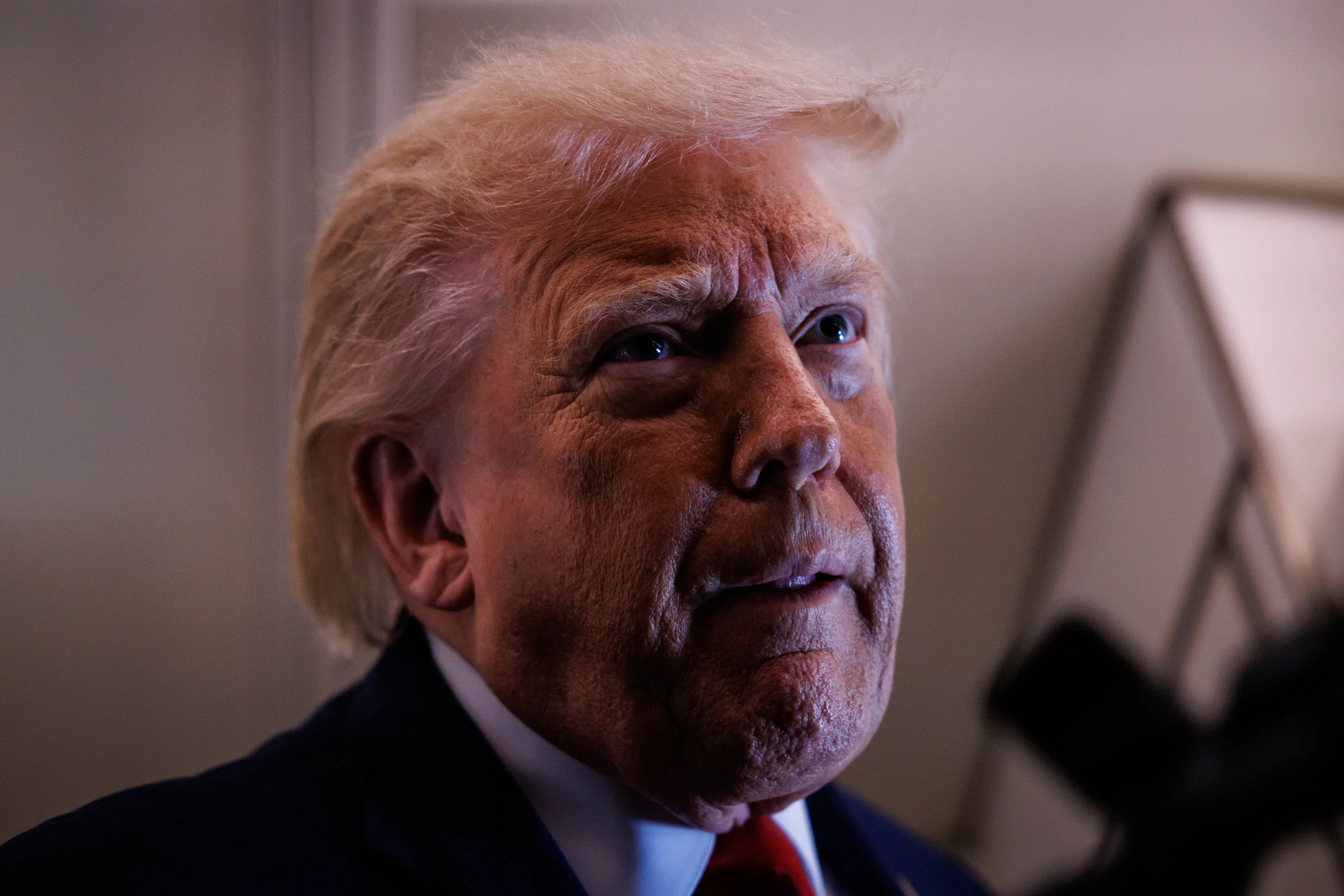 Donald Trump tucks his bottom lip and looks up while speaking to reporters on Air Force One