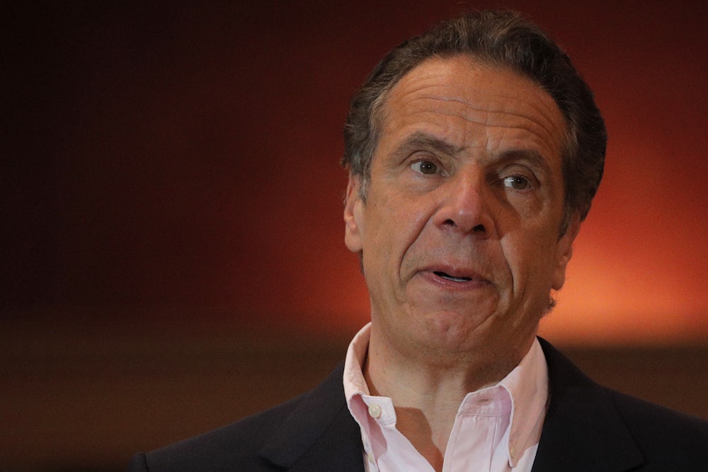 New York Governor Andrew Cuomo stands against a backdrop of red light