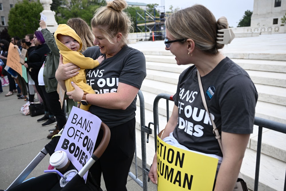 Two pro-choice demonstrators talk, as one holds a baby.