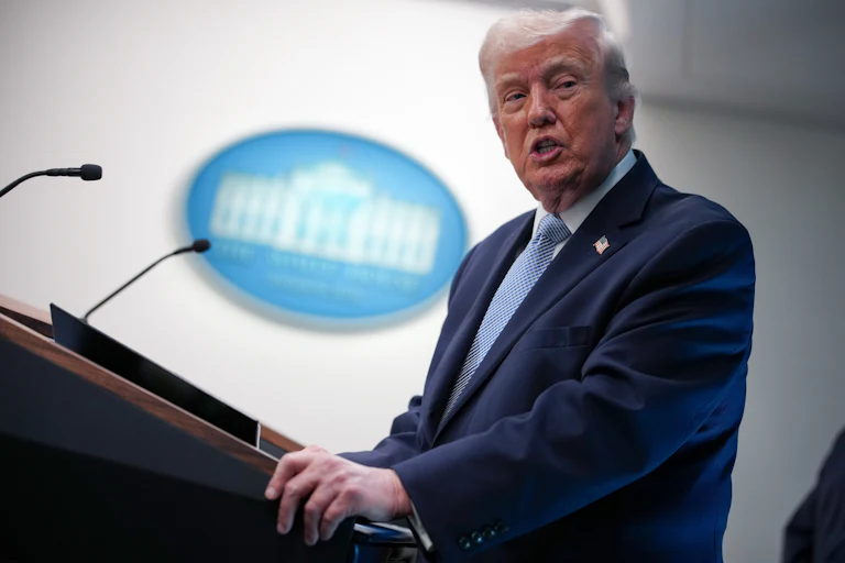 President Donald Trump stands behind a podium in the White House briefing room