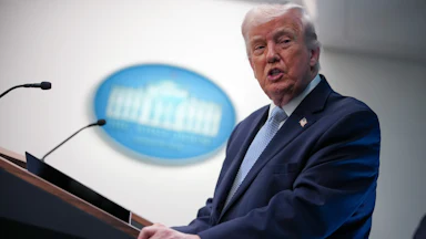 President Donald Trump stands behind a podium in the White House briefing room