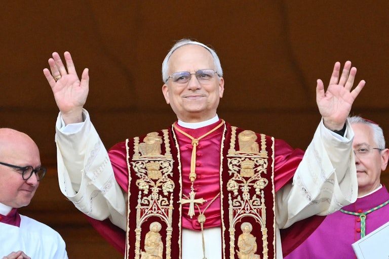 Robert Prevost, aka Pope Leo IVX, waves both hands from the Vatican balcony.