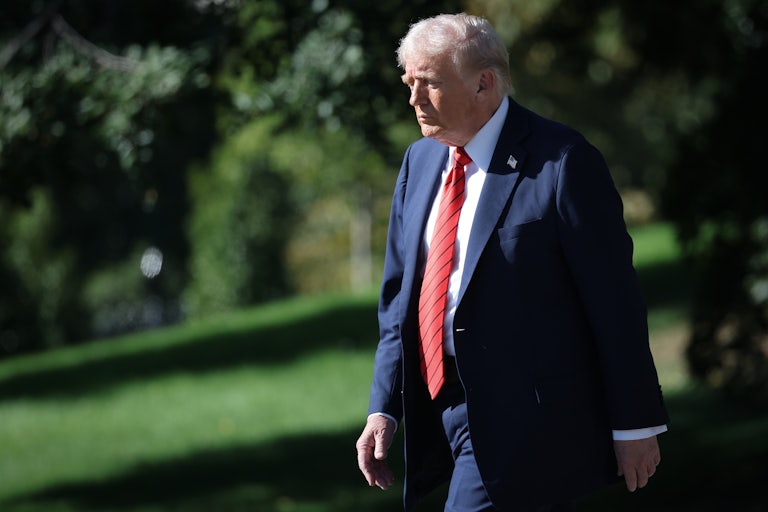 Donald Trump looks down while walking outside the White House