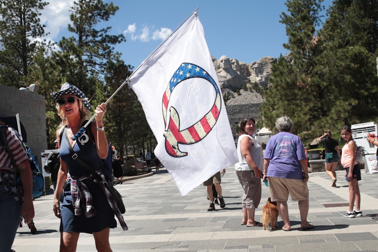A Donald Trump supporter holding a QAnon flag visits Mount Rushmore National Monument