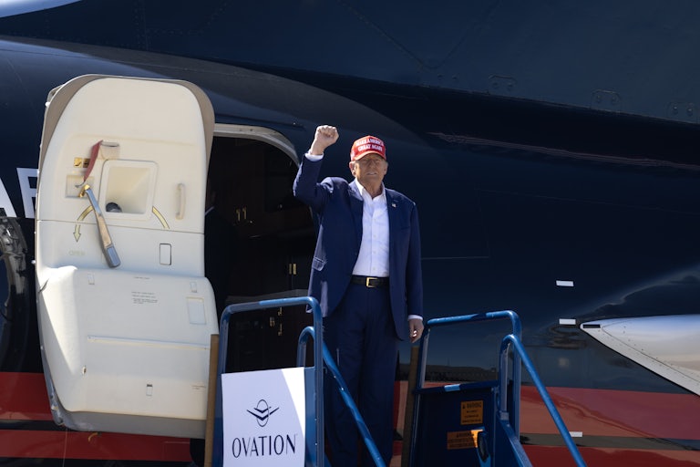 Donald Trump raises his fist as he gets off his plane