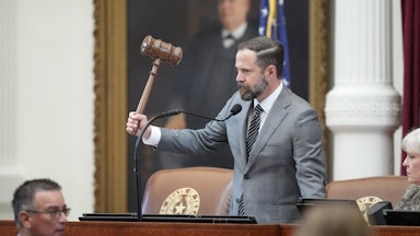 Texas state House Speaker Dustin Burrows holds up a very large gavel while standing at the dais in the state Capitol