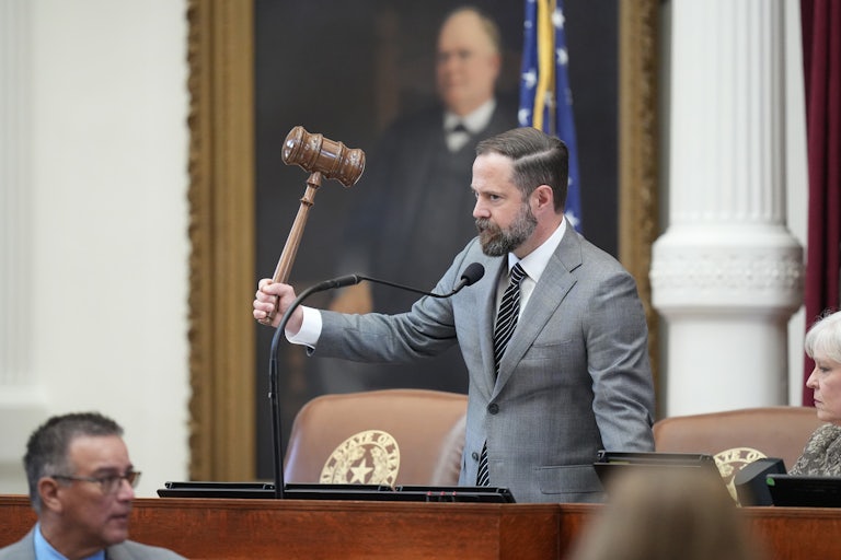 Texas state House Speaker Dustin Burrows holds up a very large gavel while standing at the dais in the state Capitol