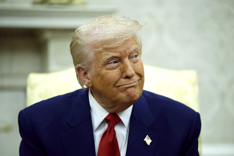 Donald Trump smiles while seated in the White House