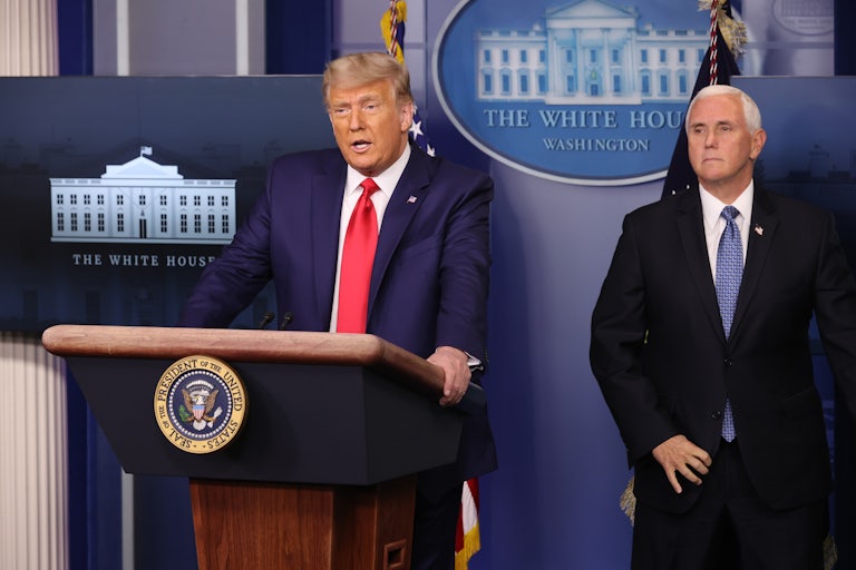 Donald Trump speaks at a podium while Mike Pence stands behind him