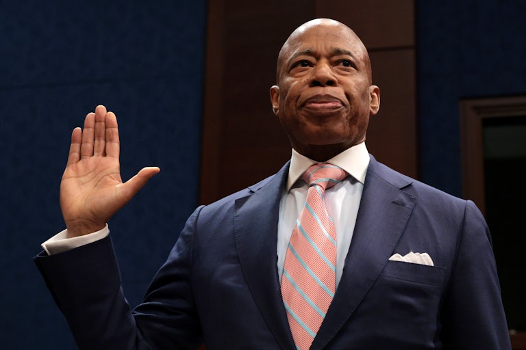 New York City Mayor Eric Adams raises his right hand as if being sworn in.