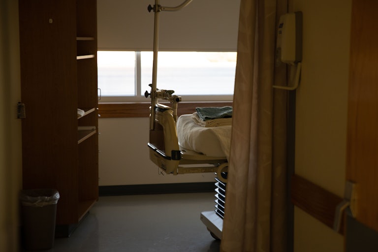 The view of a hospital bed from a doorframe.