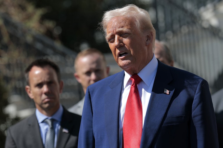 Donald Trump speaks outside the White House while three men stand behind him.