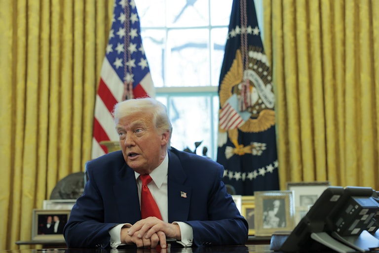 Donald Trump speaks to reporters while sitting at his desk in the Oval Office