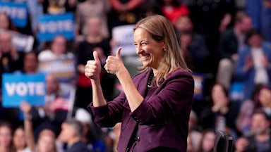 Democratic Governor-elect Mikie Sherill gives two thumbs up as she's seated on a stage at a campaign rally.