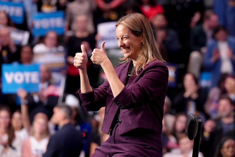 Democratic Governor-elect Mikie Sherill gives two thumbs up as she's seated on a stage at a campaign rally.