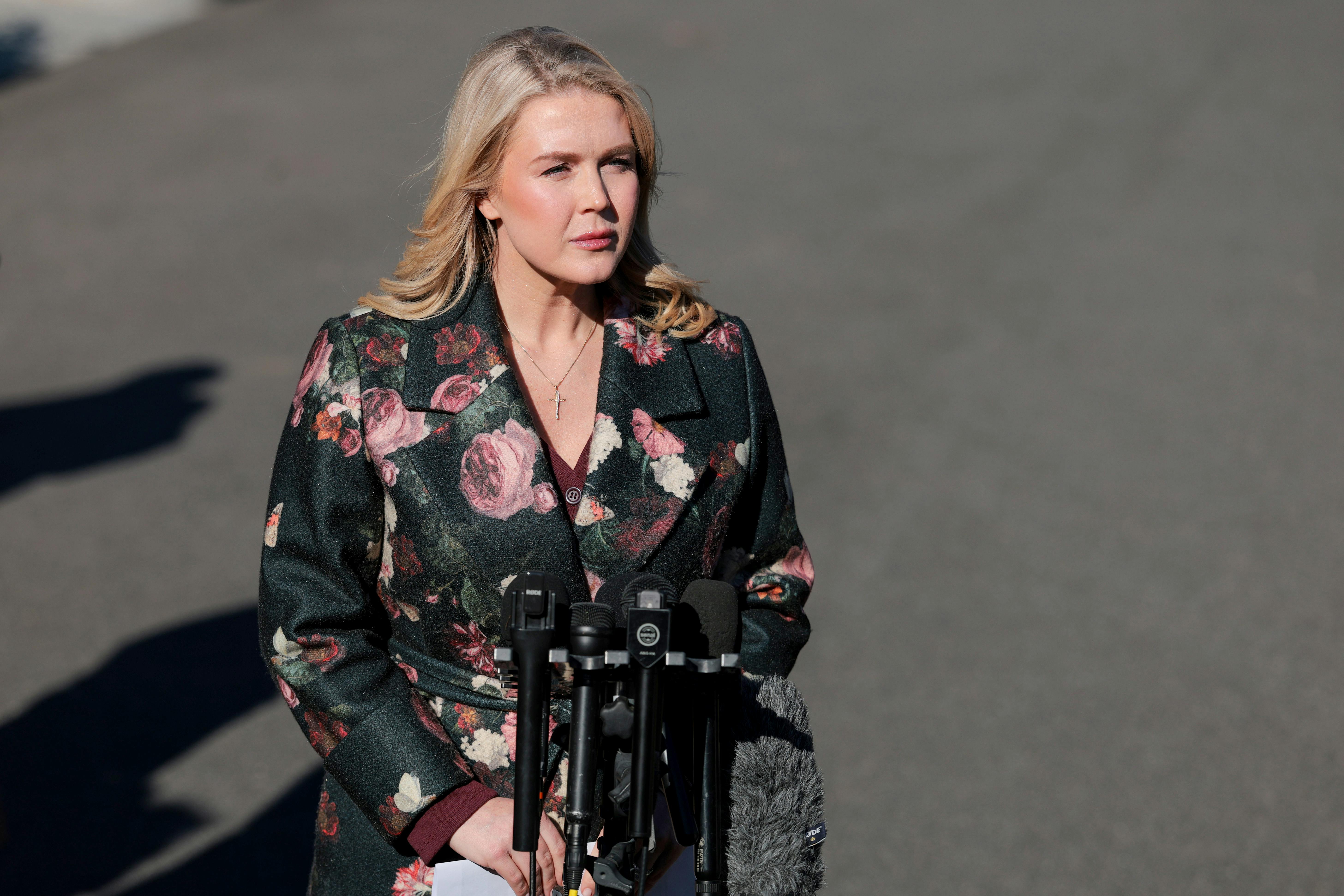 Press secretary Karoline Leavitt stands in front of reporters' microphones outside the White House