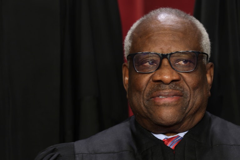 Supreme Court Justice Clarence Thomas looks off camera and smiles weirdly