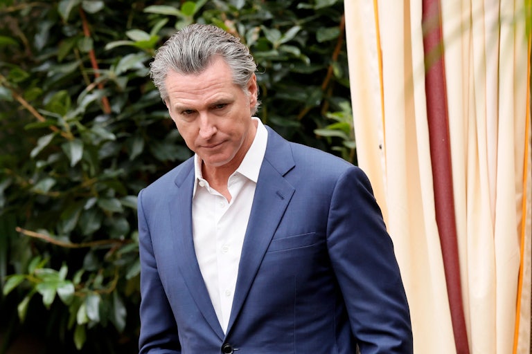 California Governor Gavin Newsom walks ouside while looking downward.