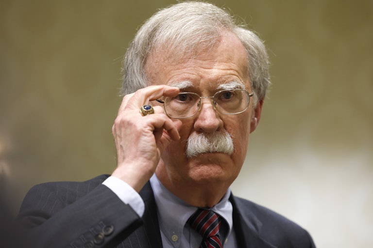 Former National Security Adviser John Bolton adjusts his glasses at a press conference.