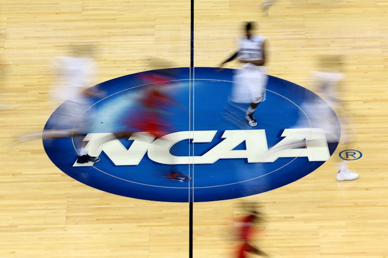 Blurry images of NCAA basketball player streak up a basketball court.
