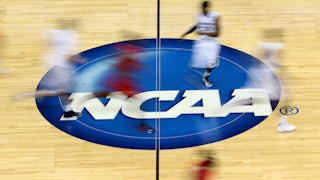 Blurry images of NCAA basketball player streak up a basketball court.
