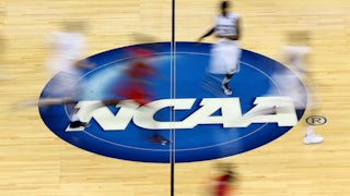 Blurry images of NCAA basketball player streak up a basketball court.