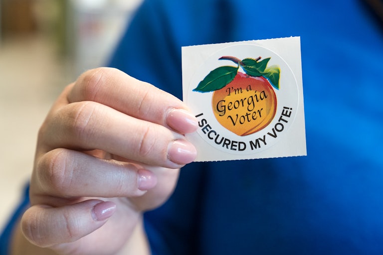 Someone holds up a Georgia “I Voted” sticker