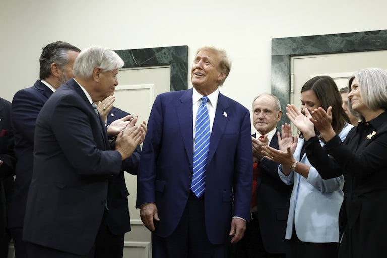 Donald Trump smiles as Republican senators stand around him and clap