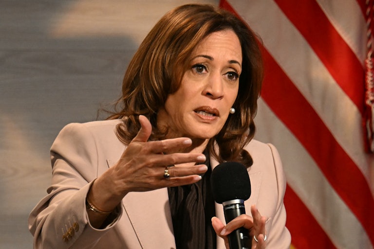 Kamala Harris holds a microphone while speaking to the National Association of Black Journalists