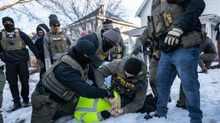Federal law enforcement agents detain a demonstrator during a raid in south Minneapolis.