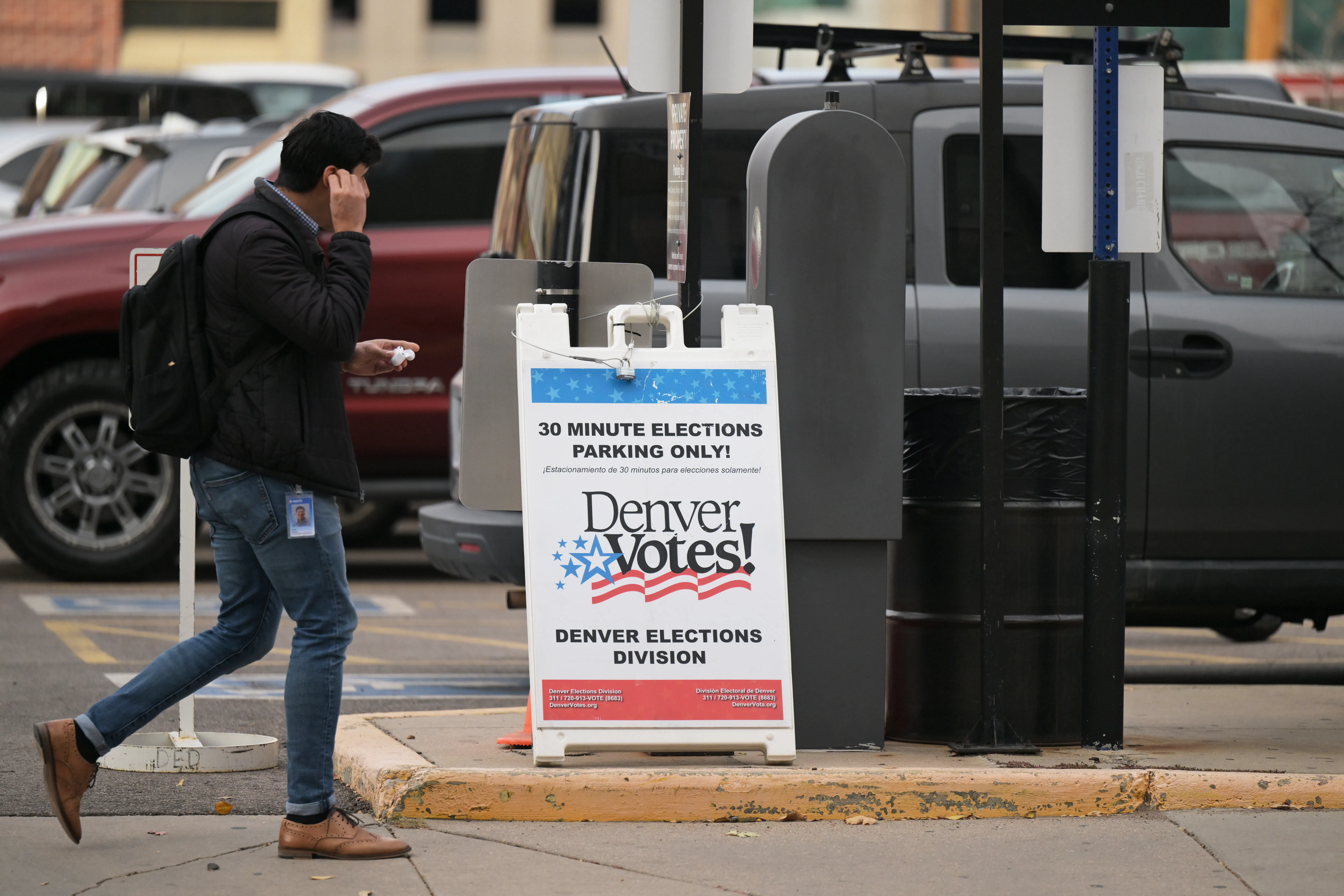 A man walks by an election sign that reads "Denver Votes!"