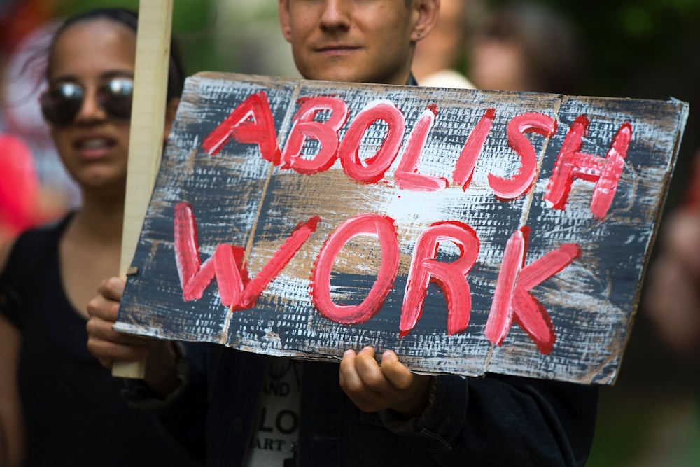 A May Day demonstrator holds a sign that reads "Abolish Work"