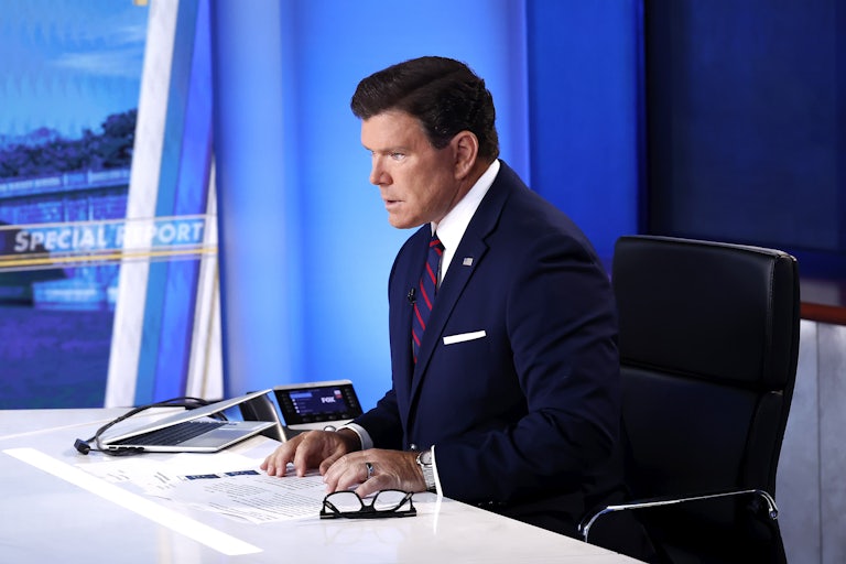 Bret Baier is seen in profile as he sits at a desk