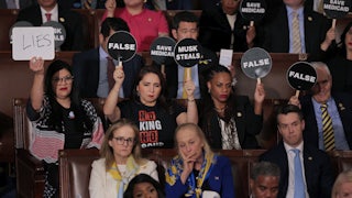 Rep. Rashida Tlaib joins fellow Democrats in holding up signs to protest against President Donald Trump as he addresses a joint session of Congress.