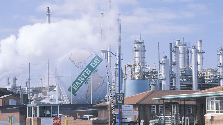 An inflatable globe rests on top of an oil refinery, reading "Earth Day 1970-1990."