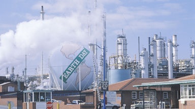An inflatable globe rests on top of an oil refinery, reading "Earth Day 1970-1990."