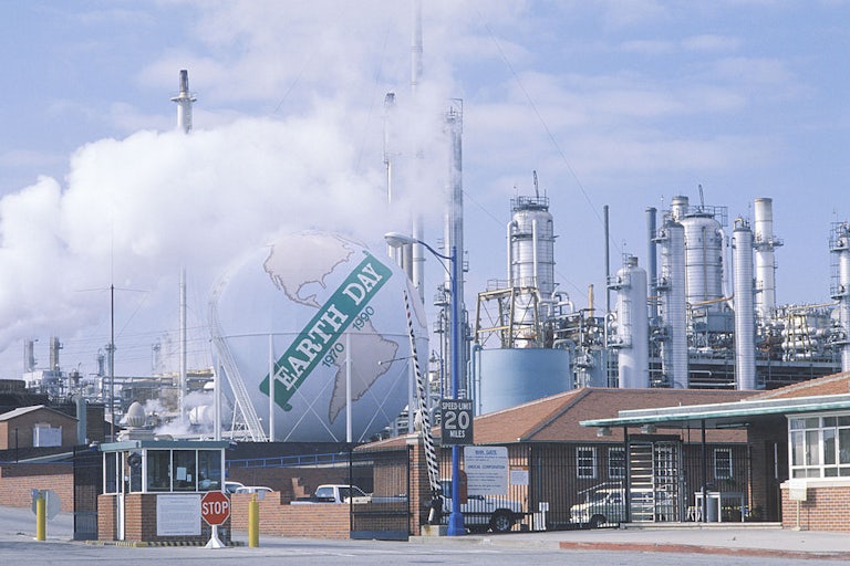 An inflatable globe rests on top of an oil refinery, reading "Earth Day 1970-1990."
