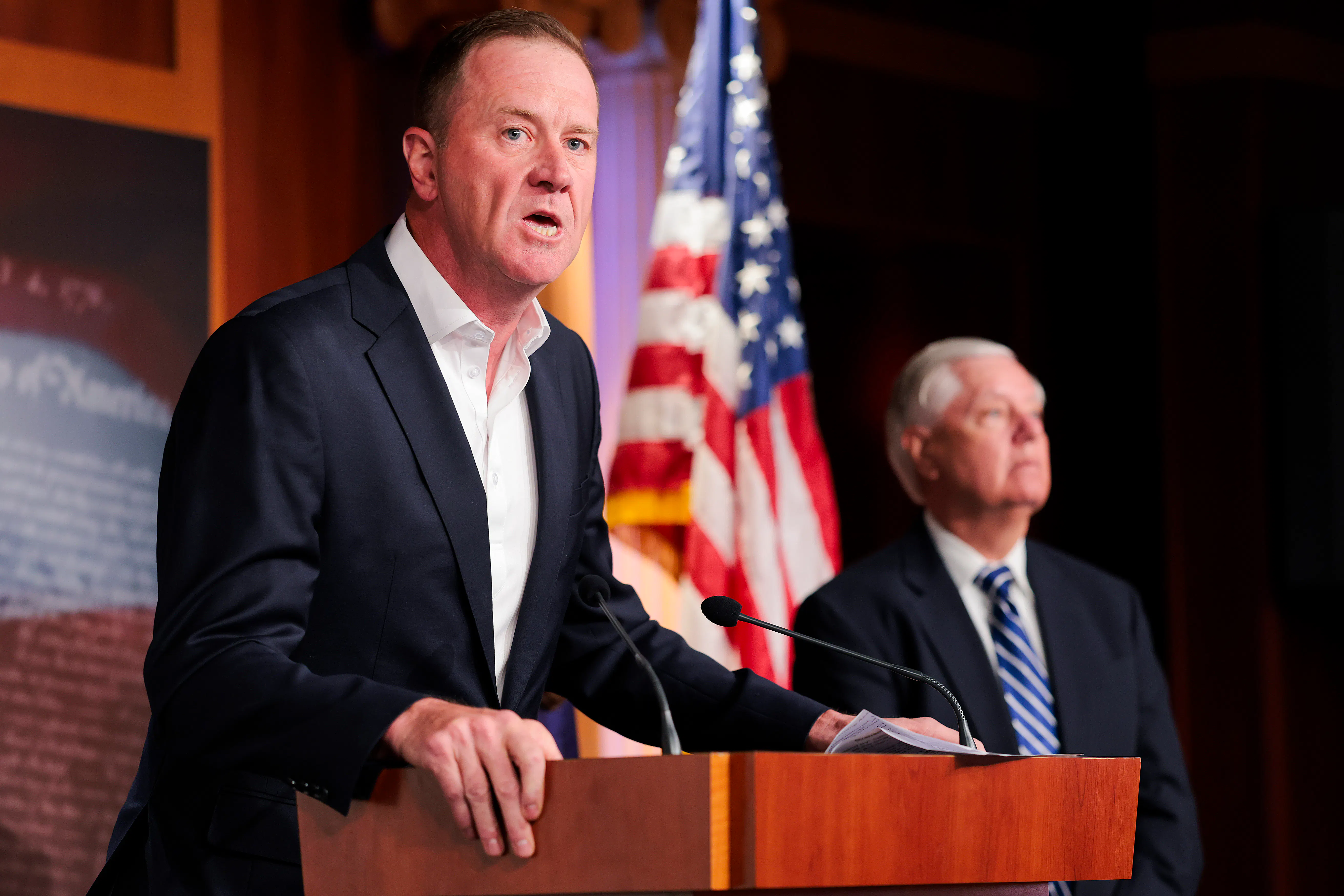 Senator Eric Schmitt leans on a podium while speaking during a press conference 