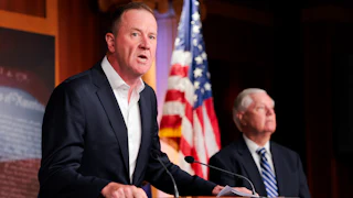 Senator Eric Schmitt leans on a podium while speaking during a press conference
