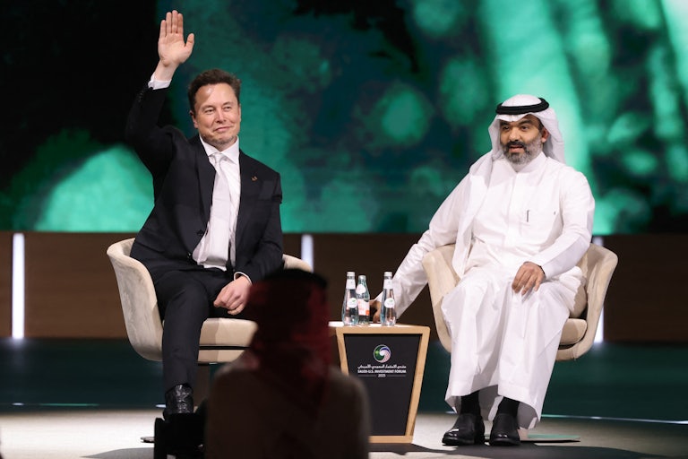 Elon Musk waves while sitting on stage in Riyadh, Saudi Arabia