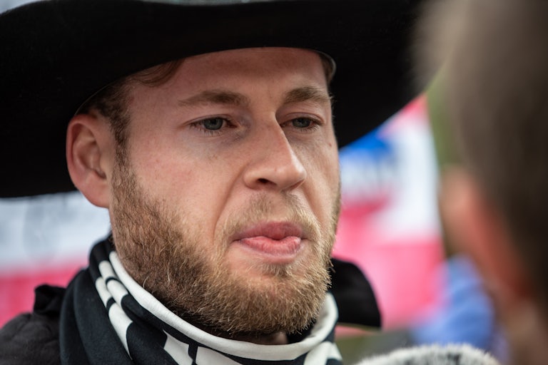 Owen Shroyer closeup (he makes a weird face and is probably wearing a black cowboy hat)