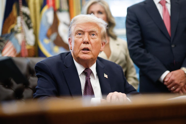 Donald Trump seems shocked while seated at his desk in the Oval Office of the White House.