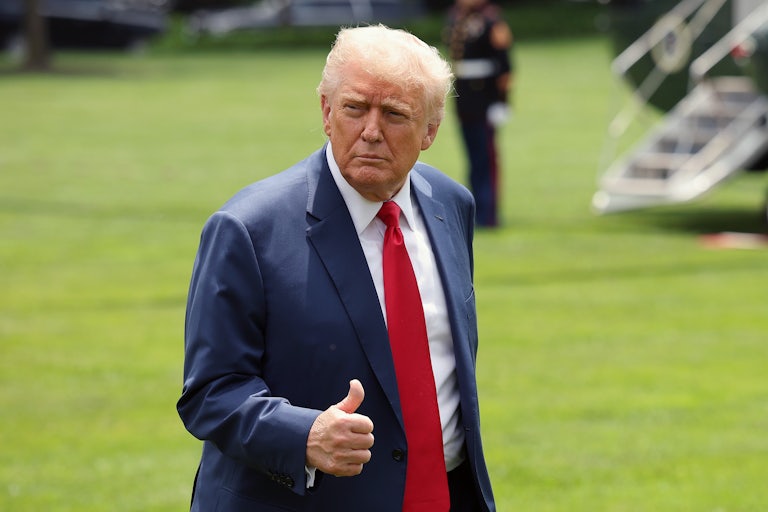 Donald Trump gives a thumbs up as he walks across the White House lawn.