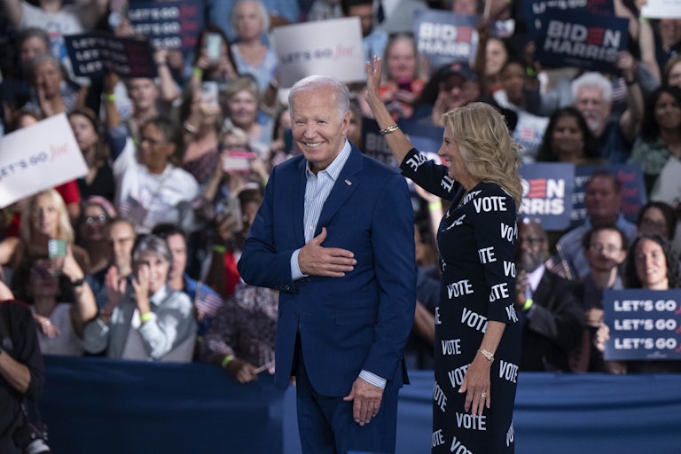 Joe Biden smiles and holds his hand over his chest as he appears before a large crowd at a political rally