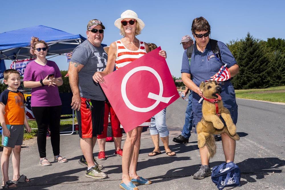 QAnon supporters hold a "Q" banner at a Trump campaign stop this summer.