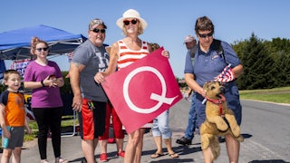 QAnon supporters hold a "Q" banner at a Trump campaign stop this summer.